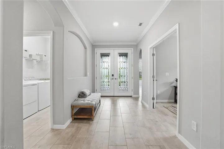 Foyer featuring light tile flooring, double entry doors with decorative glass panels, and crown molding