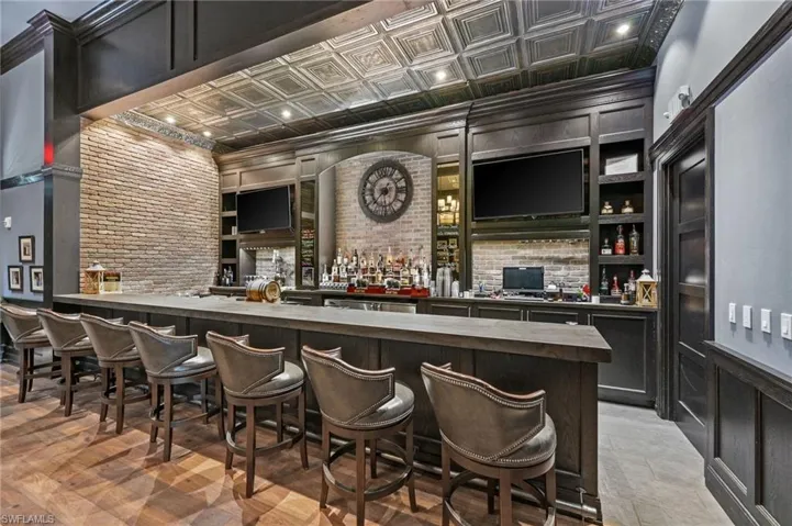 Custom-built bar featuring wood-finish flooring, exposed brick accents, and a distinctive pressed tin ceiling