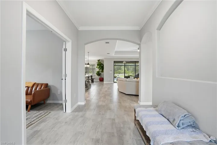 Entryway featuring wood-finish flooring, a cased opening, crown molding, and an arched doorway leading to living spaces