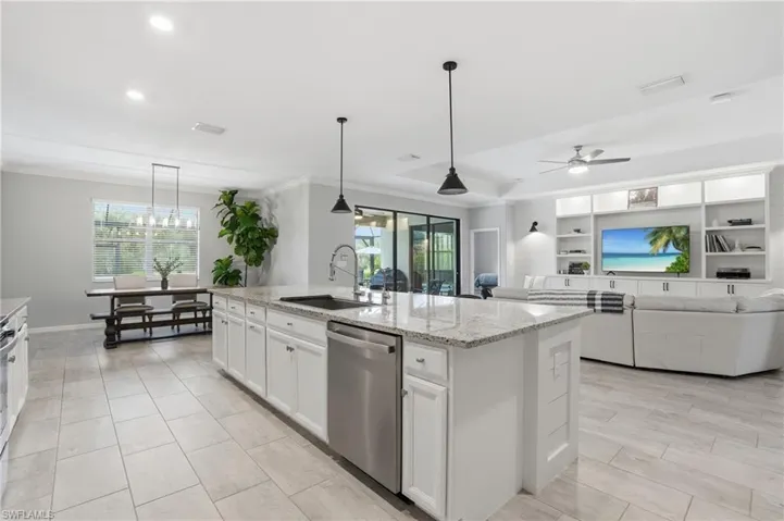 Spacious open-concept interior featuring a substantial kitchen island with granite countertops, stainless steel appliances, and white cabinets