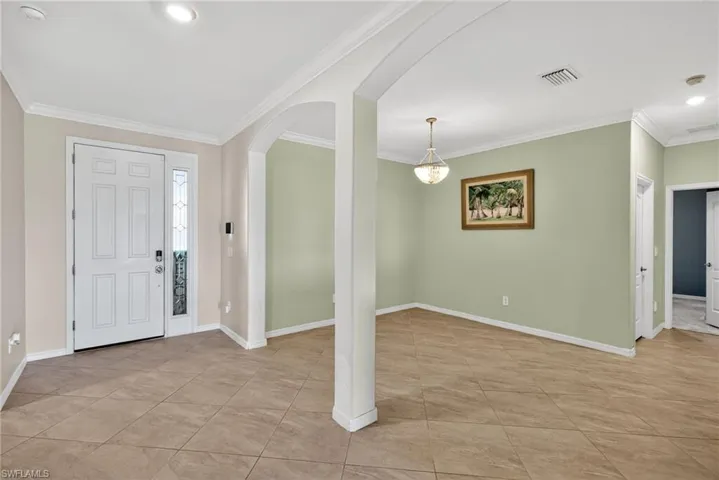 Entrance foyer featuring arched walkways, crown molding, recessed lighting, and light tile patterned floors
