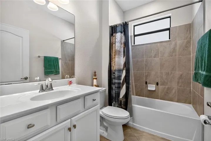 Bathroom with shower / tub combo with curtain, vanity, and light tile patterned floors
