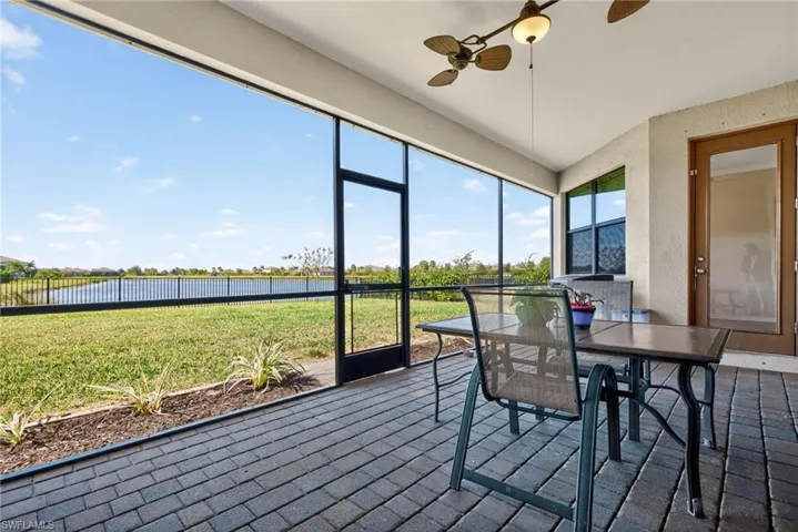 Sunroom / solarium featuring brick floors, a textured wall, and a water view