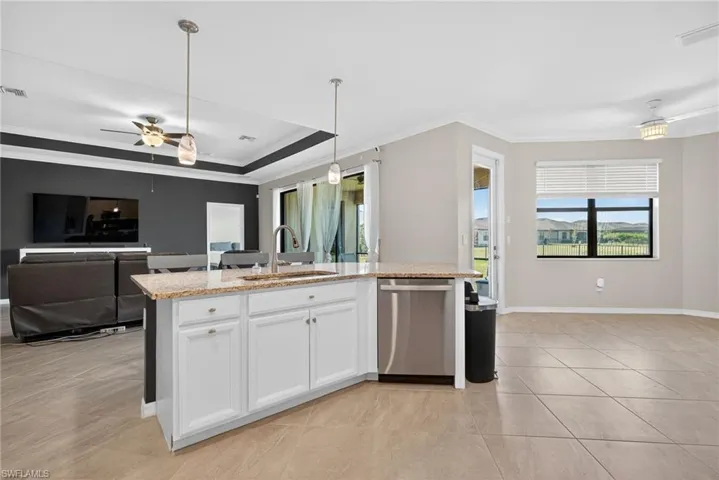 Kitchen with ornamental molding, open floor plan, a raised ceiling, dishwasher, and white cabinets