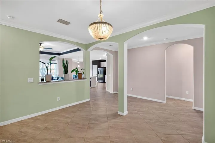 Spare room featuring crown molding, light tile patterned floors, and arched walkways