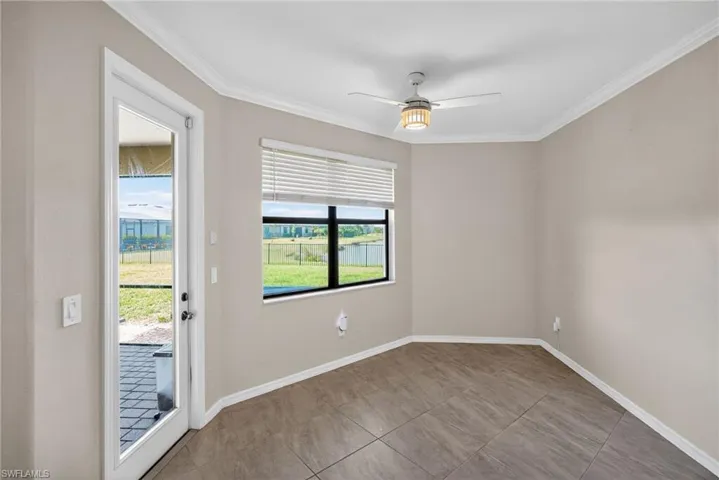 Empty room featuring crown molding, a ceiling fan, and light tile patterned floors