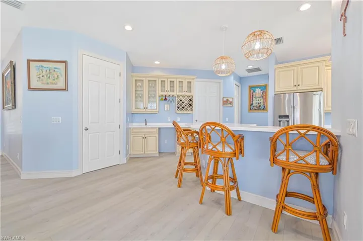 Kitchen featuring a kitchen bar, light wood-type flooring, stainless steel fridge, and cream cabinetry