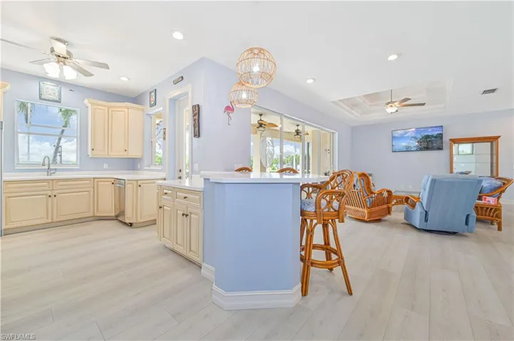 Kitchen featuring ceiling fan, a tray ceiling, a kitchen breakfast bar, and light hardwood / wood-style floors