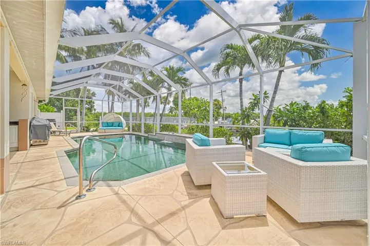 View of pool with a patio, glass enclosure, and an outdoor hangout area