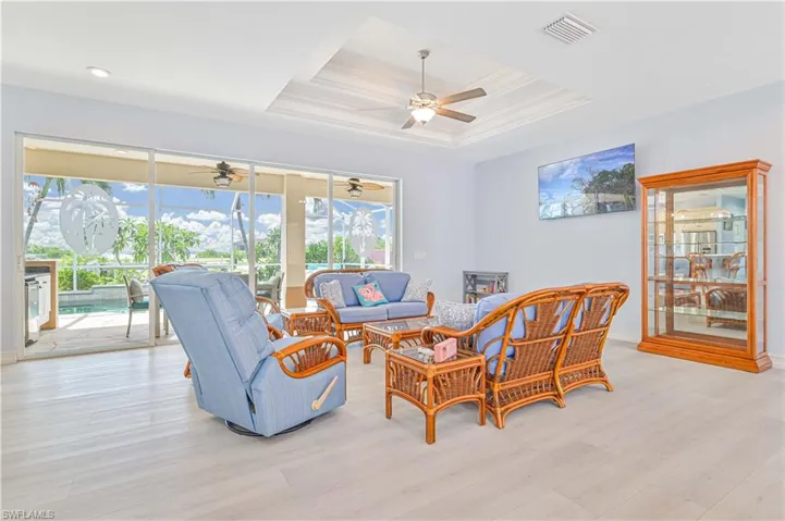 Living room featuring light hardwood / wood-style floors, a raised ceiling, and ceiling fan