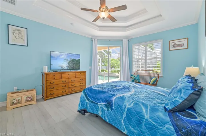 Bedroom with a raised ceiling, crown molding, access to outside, ceiling fan, and wood-type flooring
