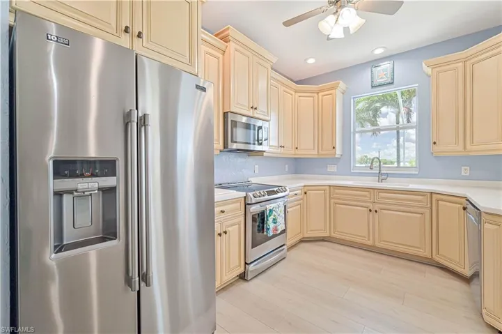 Kitchen featuring appliances with stainless steel finishes, tasteful backsplash, sink, light brown cabinetry, and ceiling fan