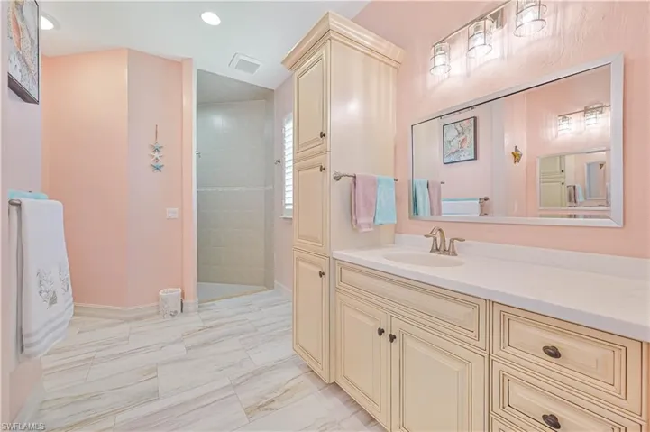 Bathroom featuring tiled shower, vanity, and tile patterned floors
