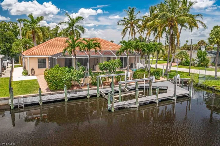 Dock area with glass enclosure, a water view, and a yard