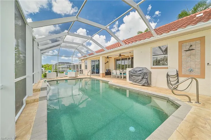 View of pool with a patio, ceiling fan, and glass enclosure