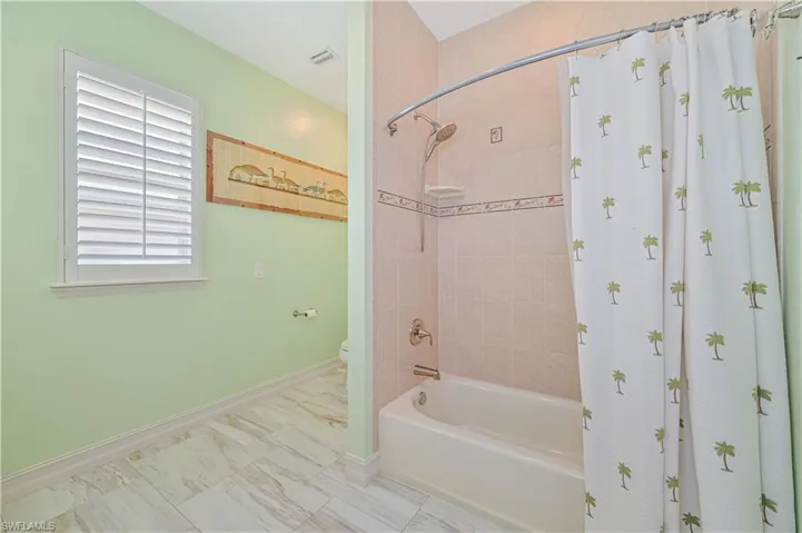 Bathroom featuring toilet, tile patterned floors, and shower / bathtub combination with curtain