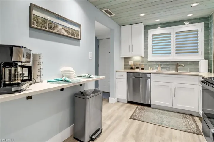 Kitchen with white cabinetry, light wood-type flooring, wood ceiling, appliances with stainless steel finishes, and sink