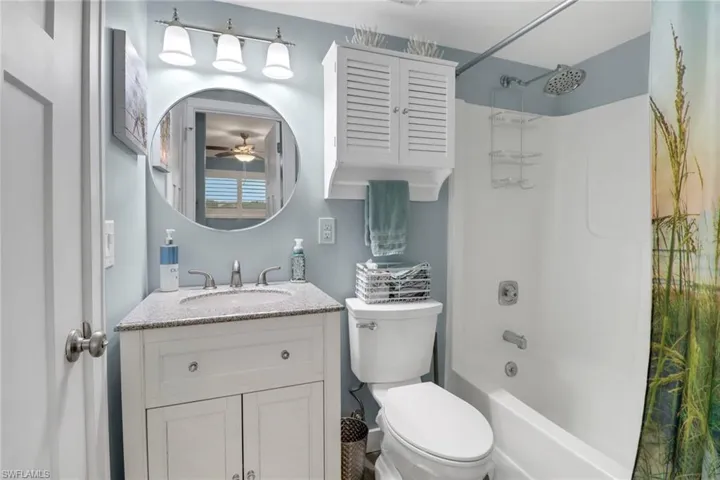 Full bathroom with vanity, toilet, ceiling fan, and shower / bath combination with curtain
