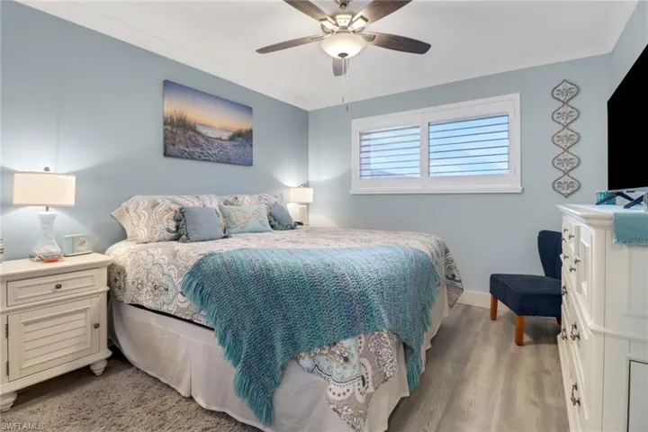 Bedroom with light hardwood / wood-style floors, ornamental molding, and ceiling fan