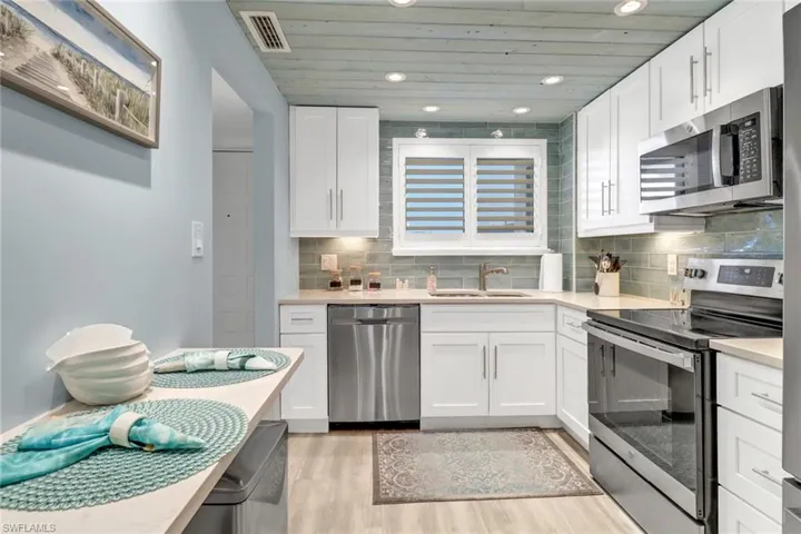 Kitchen featuring sink, appliances with stainless steel finishes, light hardwood / wood-style floors, and white cabinetry