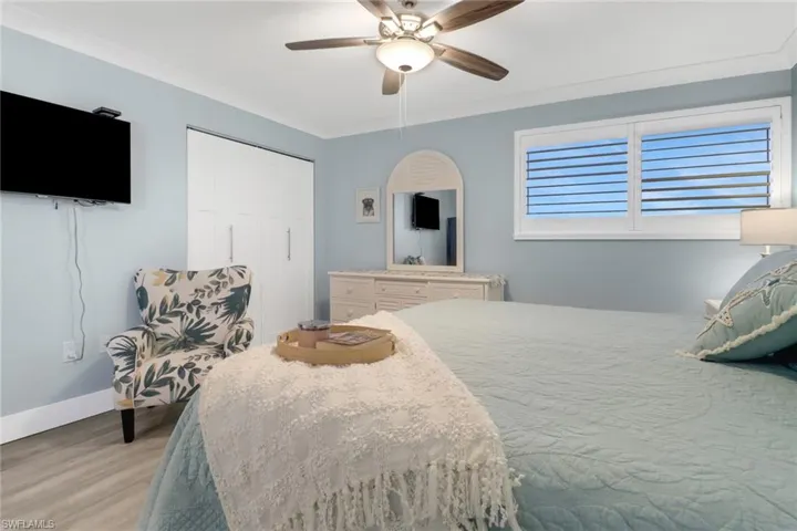 Bedroom with light hardwood / wood-style floors, crown molding, a closet, and ceiling fan