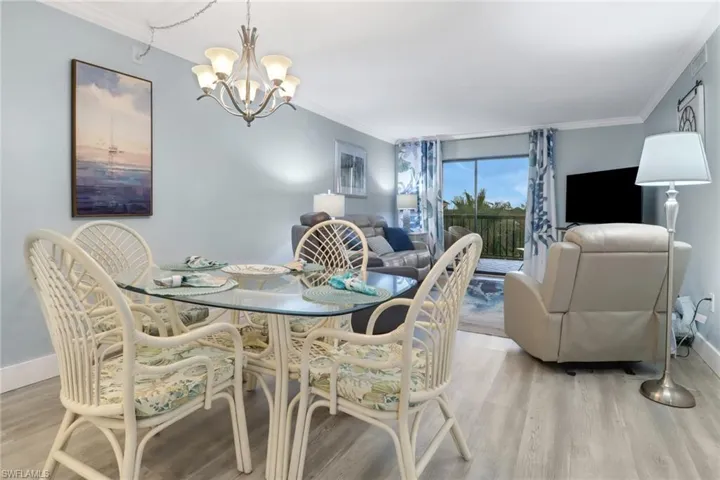 Dining room with a notable chandelier, crown molding, and light wood-type flooring