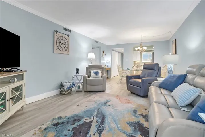 Living room featuring light hardwood / wood-style flooring, crown molding, and a chandelier