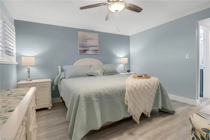 Bedroom with ceiling fan, crown molding, light hardwood / wood-style flooring, and multiple windows