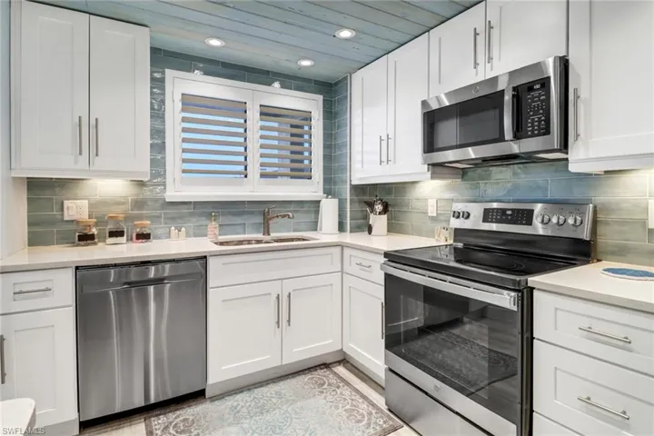 Kitchen featuring sink, tasteful backsplash, white cabinets, and stainless steel appliances