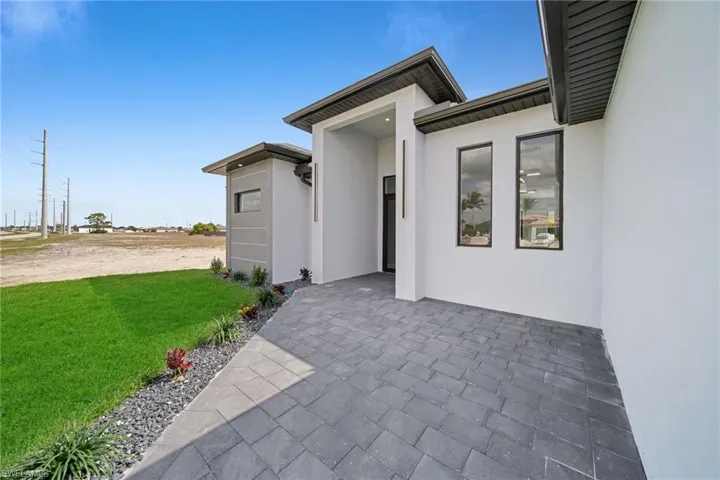 Entrance to property featuring a patio area and a lawn