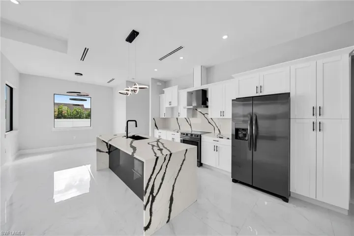 Kitchen featuring light tile patterned flooring, white cabinets, a kitchen island with sink, stainless steel appliances, and pendant lighting