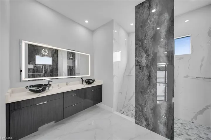 Bathroom featuring tile patterned flooring, dual vanity, and a tile shower