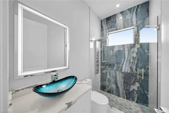 Bathroom featuring a shower with shower door, vanity, and toilet