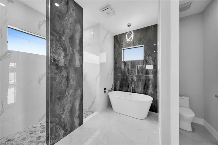 Bathroom featuring plus walk in shower, tile patterned flooring, a healthy amount of sunlight, and tile walls