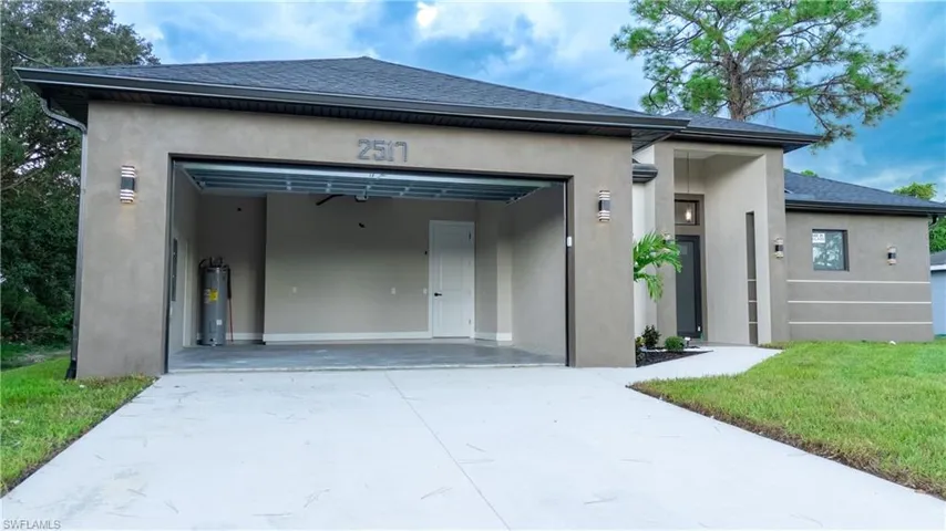 Modern stucco exterior with dark trim accents, concrete driveway, and an attached garage