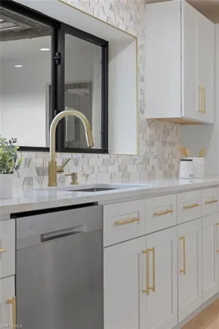 Kitchen featuring sink, light hardwood / wood-style floors, decorative backsplash, white cabinetry, and dishwasher