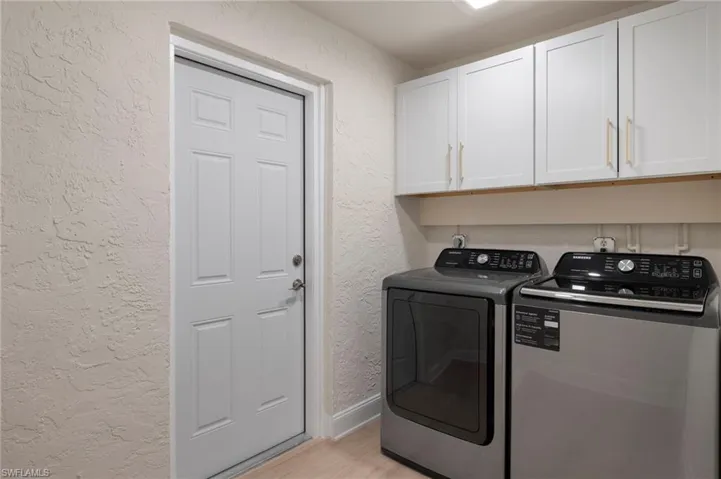 Washroom featuring separate washer and dryer, light wood-type flooring, and cabinets