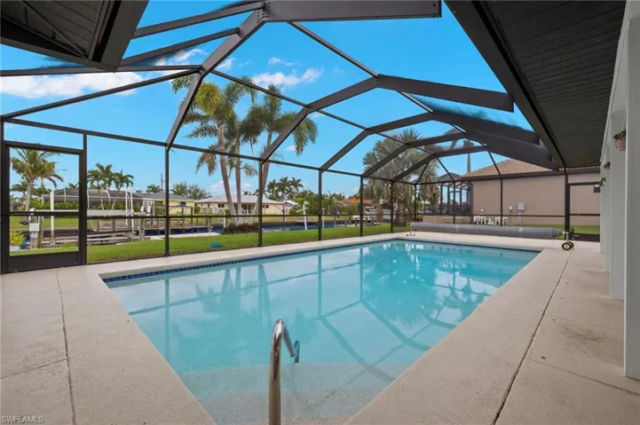 View of pool with a patio area and glass enclosure