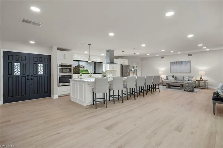 Kitchen featuring decorative light fixtures, extractor fan, white cabinets, a kitchen island, and light hardwood / wood-style floors