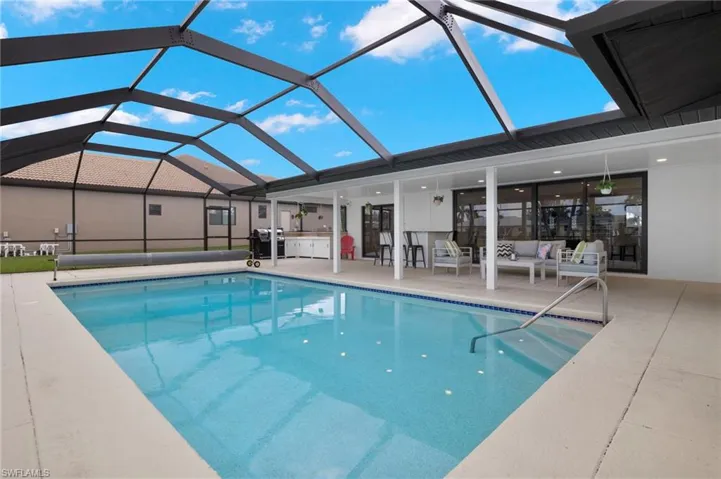 View of swimming pool with area for grilling, an outdoor living space, glass enclosure, and a patio area
