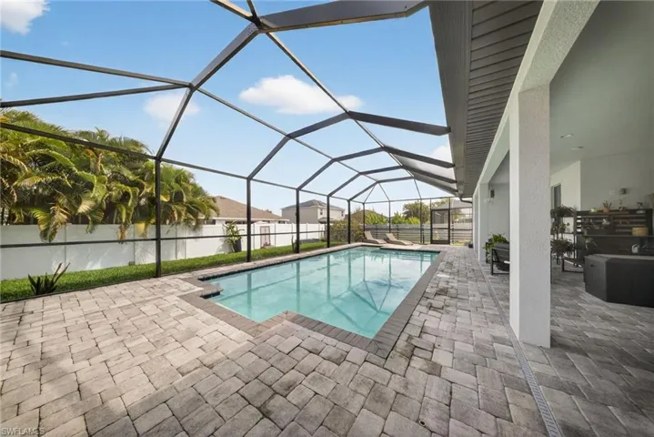 View of pool with a sunroom, glass enclosure, patio surround, and a fenced backyard