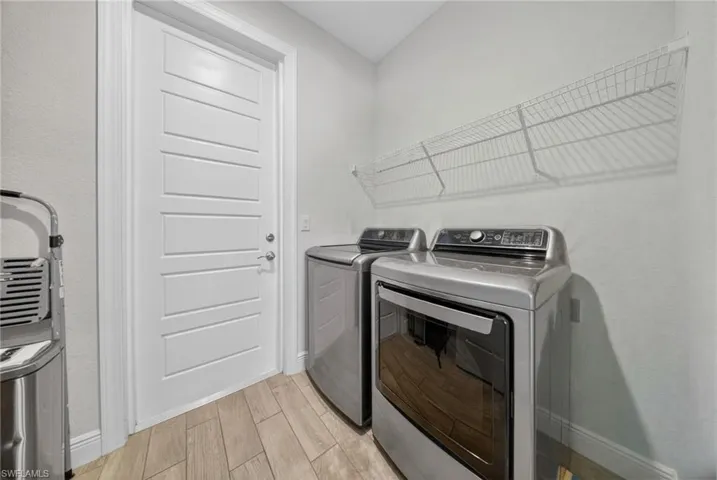 Laundry area with wood finish floors and washing machine and clothes dryer