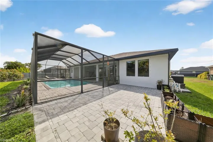 Back of property with a sunroom, glass enclosure, a patio area, stucco siding, and a yard