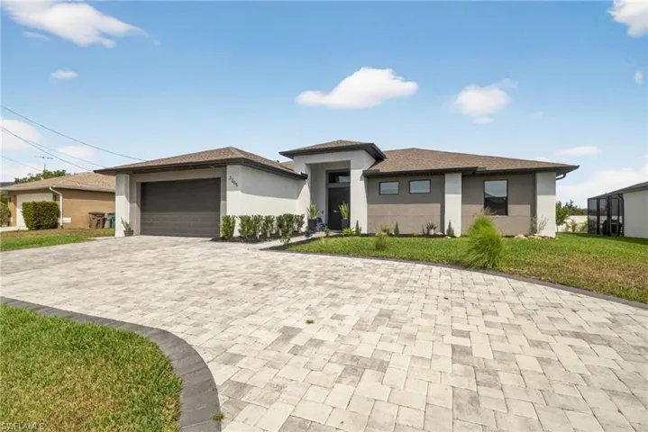 Prairie-style house featuring stucco siding, a front lawn, and decorative driveway