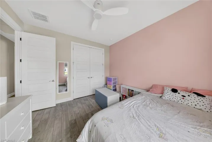 Bedroom with a closet, dark wood finished floors, and a ceiling fan