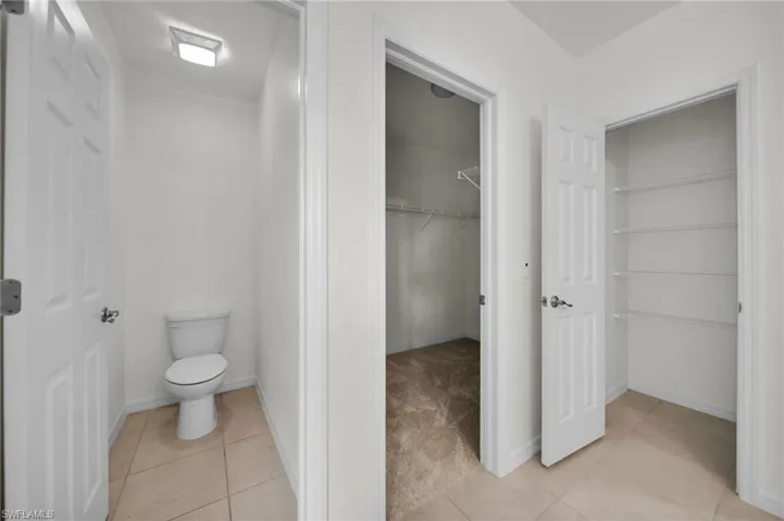 Bathroom with a walk in closet and light tile patterned floors