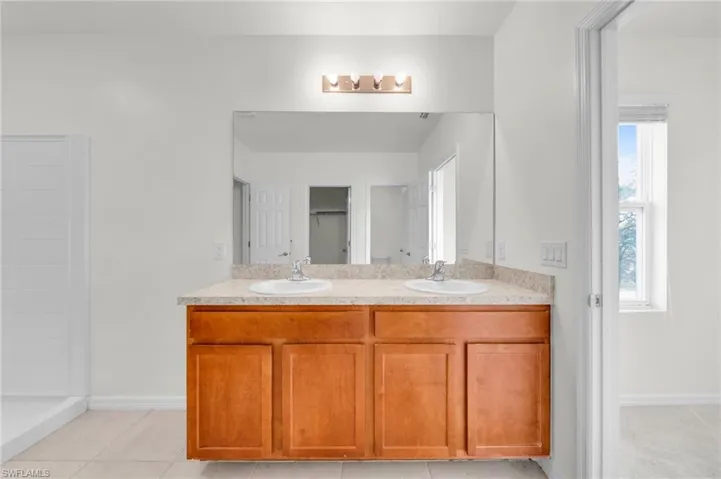 Bathroom featuring double vanity and a spacious closet