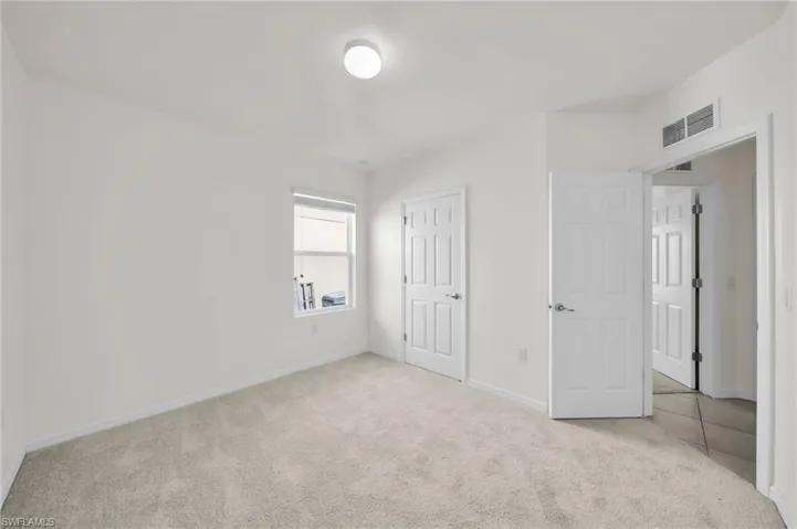Unfurnished bedroom with light carpet and baseboards