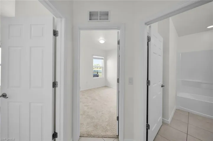 Hall featuring light colored carpet and light tile patterned floors