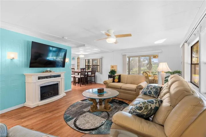 Living room with ceiling fan, a high end fireplace, and light hardwood / wood-style flooring